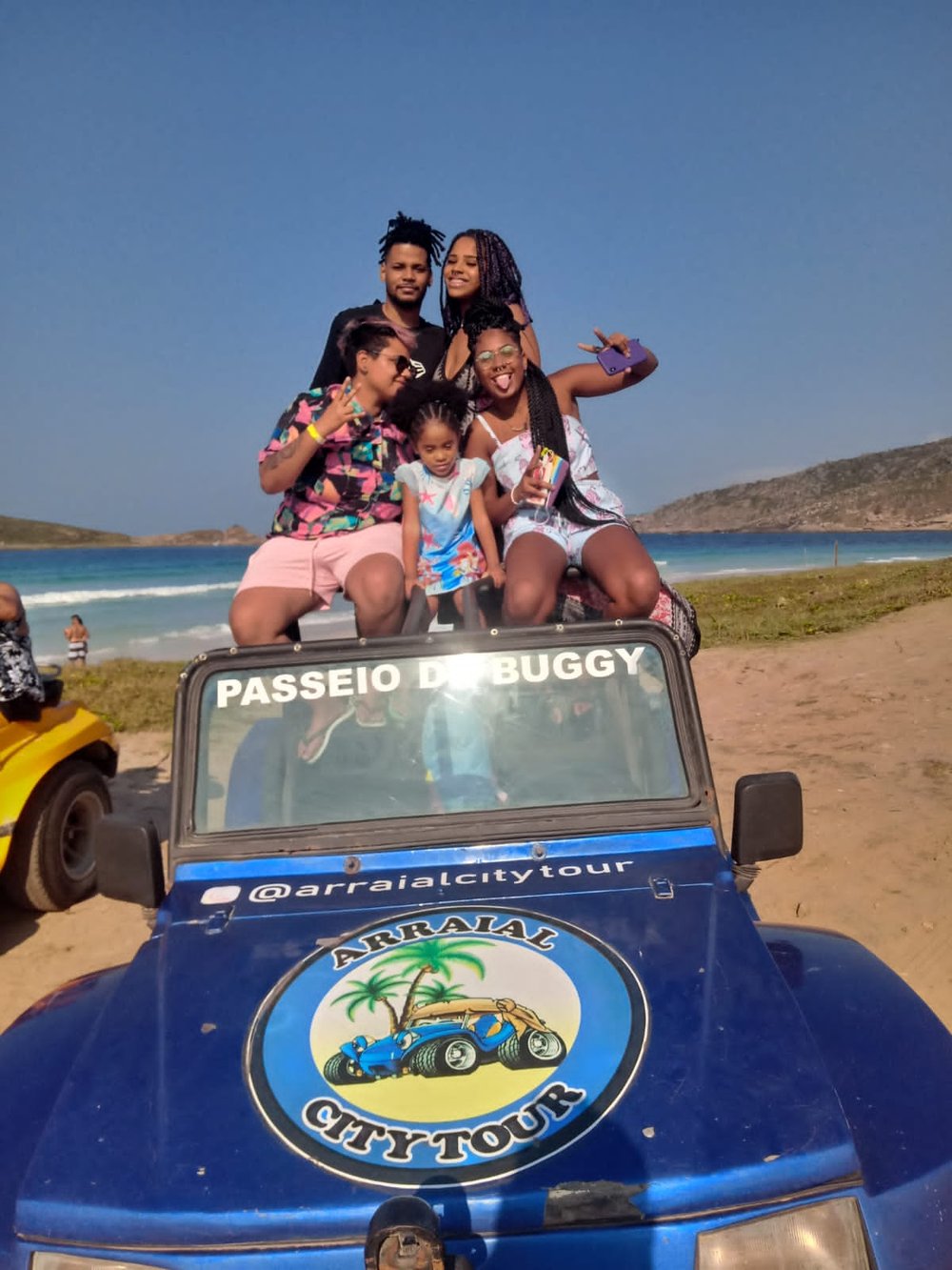 Família em cima do buggy da Arraial City Tour com a praia ao fundo