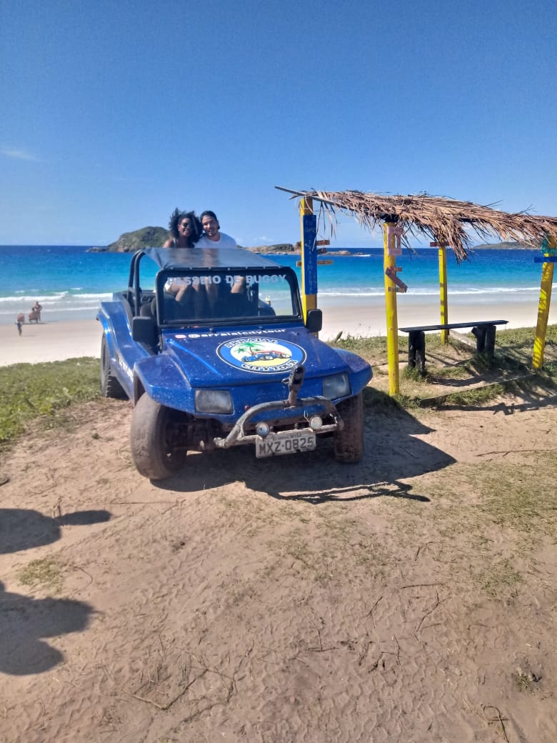 Casal no buggy azul da Arraial City Tour em frente ao mar